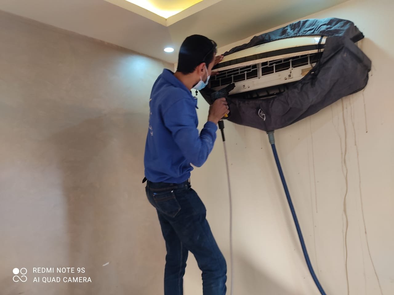 فني من إيزي هوم يغسل مكيف سبليت داخلي مغطى بجراب حماية